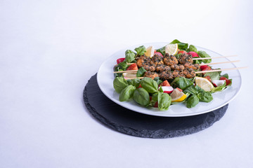 a plate of shrimp on sticks and vegetables stands on a black tray on the table