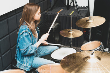 Creativity and music. Young beautiful girl plays the drums. Recording Studio. Musical equipment.