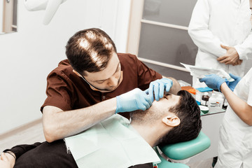 A young male dentist doctor treats a patient. Medical manipulations in dentistry, surgery....