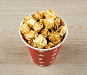 red cardboard cup with sugar popcorn on a wooden table