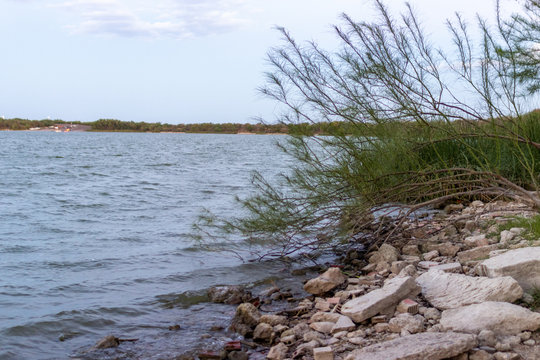 A Large Lake, The Banks Are Strewn With Huge Stones. On The Lake On A Summer Evening. Lake Casa Blanca, Texas, USA