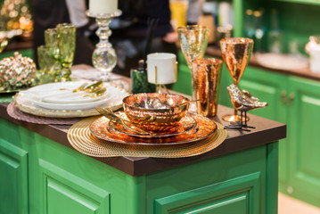 Copper and bronze color tableware. In the green kitchen, a set of glass beautiful modern dishes