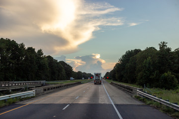20 August 2018 / Louisiana, USA: Cars and trucks drive along the asphalt road at sunset in the...