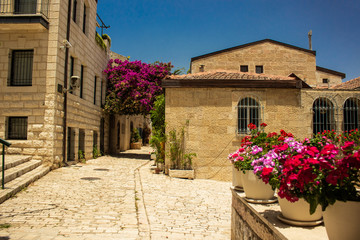 Naklejka na ściany i meble Jerusalem Israeli ancient city street landmark urban view paves road and stone small building and flowers vases landscaping outside environment in sunny summer clear weather day without people here