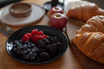 Berries , croissants, red apples on a wooden table