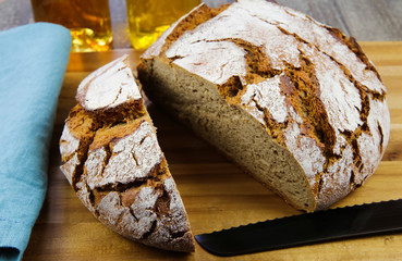 Close up of fresh made german stoneoven bread, cut slice and brown white loaf with crunchy crust on wooden cutting board