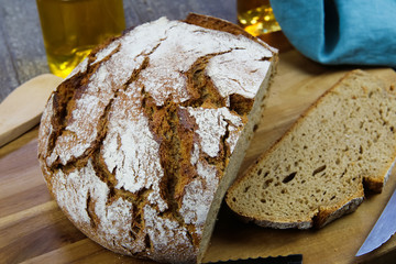 Close up of fresh made german stoneoven bread, cut slice and brown white loaf with crunchy crust on wooden cutting board