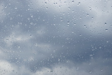 Regentropfen Wassertropfen auf Fensterscheibe mit Wolken Himmel im Hintergrund