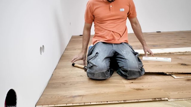 Handwerker verlegt holzboden Parkett in einem modernem haus. 4k Video in zeitlupe