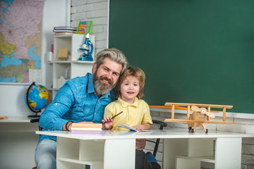 Elementary school tutor. Home school for pupil. Individual teaching. Elementary school classroom. Funny little child with father having fun on blackboard background.