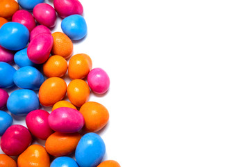 Pile of many multi-colored pea candies of blue, red and orange colors isolated on a white background. Sweet background. Copy space for text.