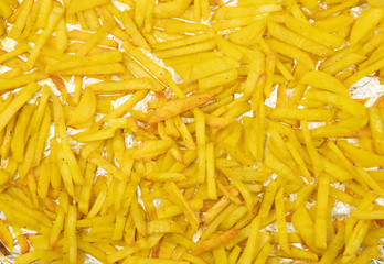 thin slices of potatoes lie on aluminum foil- cooked on a baking sheet, saturated yellow color