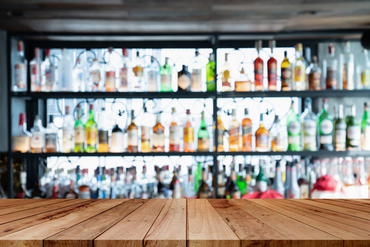 image of wooden table in front of abstract blurred background of bar lights.Blur bar or cafe restaurant with abstract bokeh light background.