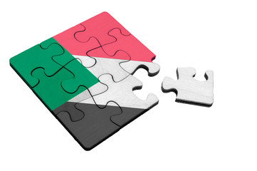 Wooden puzzle with the flag of Sudan with a breakaway piece. The concept of disputed territories and separatism in Sudan. White isolated background.