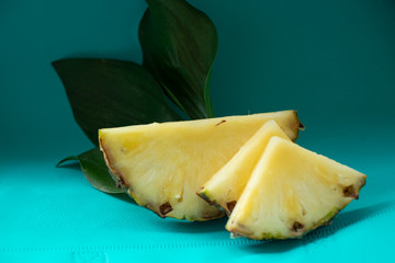 Sliced Pineapple on a turquoise background. Juicy fruit - summer mood with bright colors. On a wooden board and on a bright blue background. Yummy.