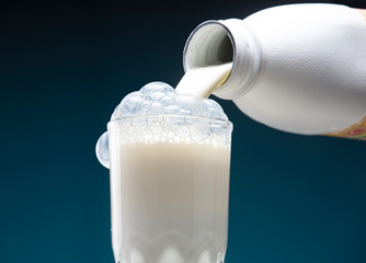 Milk is poured from a bottle into a glass. Milk is bubbling over a glass.
