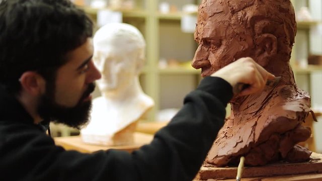 Clay sculptor making a clay bust in an art studio
