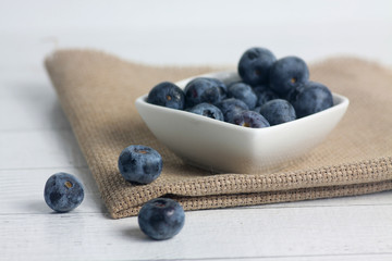 a bowl of blueberry on canvas napkin on wooden table