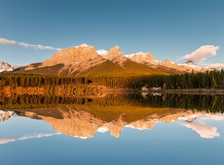 Sunrise on Mount Rundle with blue sky reflection on Rundle Forebay reservoir in autumn at Canmore