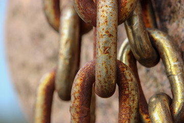 Large links of a chain of yellow metal on a stone background