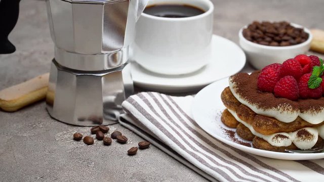 portion of Classic tiramisu dessert with berries, espresso, coffee maker on grey concrete background