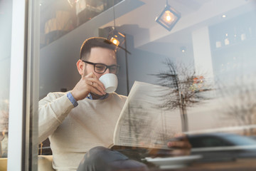 Man reading newspapers and drinking coffee - Powered by Adobe