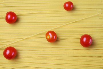 Dried spaghetti with cherry tomatoes background. Creative food pattern. Ingredients for pasta