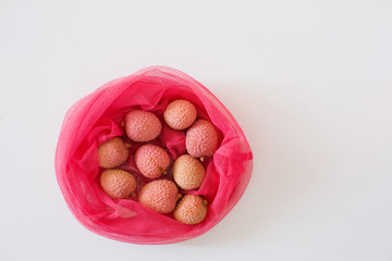 Fresh lychee in pink eco bag isolated on the white background.