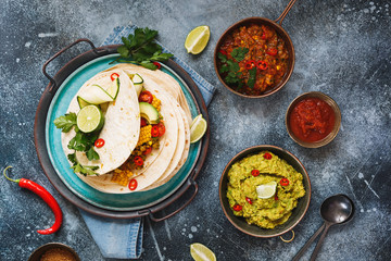 Vegetarian breakfast burrito and ingredients. Homemade tortillas stacks with veggie mince, vegetables, guacamole and avocado . Filling, colorful and delicious. Top view, blank space