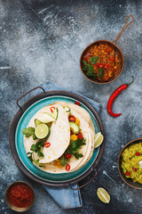 Vegetarian  burrito in the making. Rustic tortilla stacks with veggie mince, vegetables, guacamole and avocado . Top view, blank space