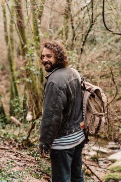 Young amn with backpack standing in forest