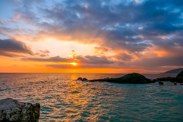 Naklejka premium Sea Dawn and Sun Rays on the Rocky Shore