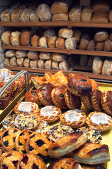 Viennoiseries on display and shelves with loaves of fresh baked bread on display in bakery