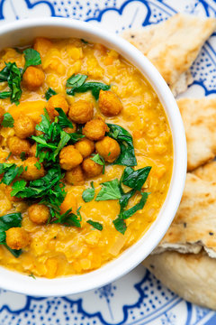 Vegan lentil curry with red lentils, sweet potatoes, spinach, roasted turmeric, chickpeas, with lime juice and coriander and naan bread