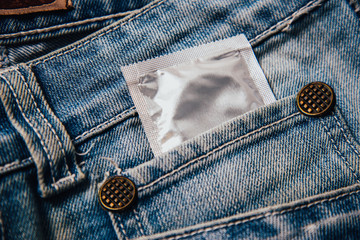 A condom in the pocket of men's denim pants. The means of contraception in jeans. Men's health and...