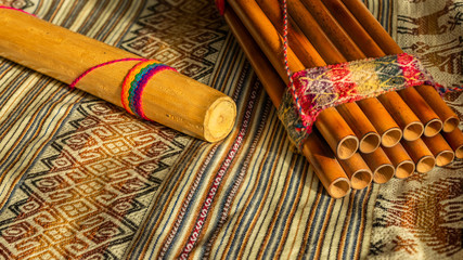 Andean instruments, Peruvian zampoña and rain stick on peruvian poncho. Concept of traditional instruments.