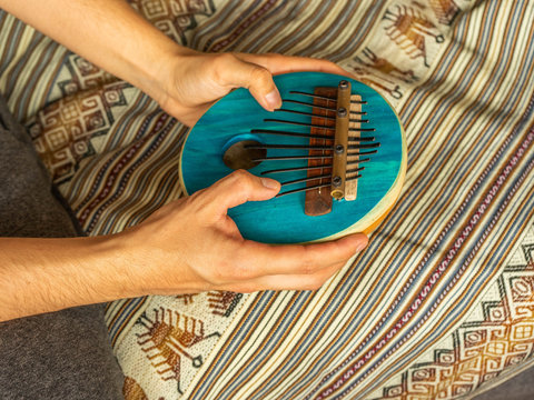 Horizontal view of a young caucasian man playing an African Kalimba. Traditional music concept.