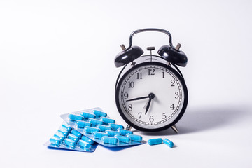 Two packages of blue capsules and a watch. Time to drink medicine. Pills for men's health and...