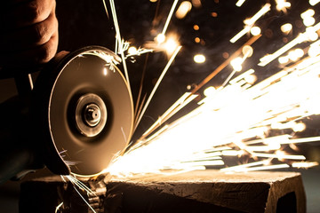 An angle grinder polishes the metal and sparks fly out of the abrasive wheel.