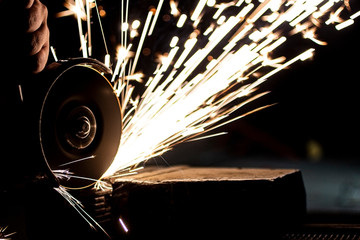 An angle grinder polishes the metal and sparks fly out of the abrasive wheel.