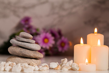 Four lighted candles with river pebbles on marble