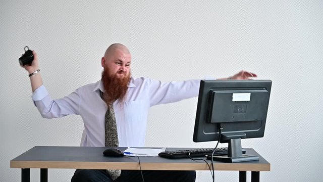 A bearded man is having a nervous breakdown at work. The office manager freaks out and breaks a mug on the monitor.