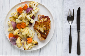 Turkey steak and vegetables cauliflower onion carrots baked in the oven on a white plate. Concept spring diet menu. Top view, flat lay