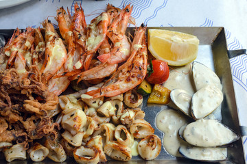 Fried seafood platter. Shrimp, squid, fish and vegetables in spicy sauce. Lunch at an old fish restaurant on the island of Cyprus. Gastronomic journey.