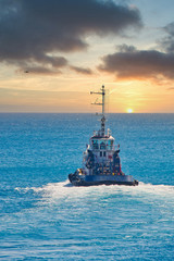 A tugboat sailing out of the harbor toward the horizon