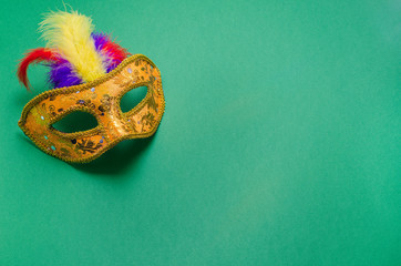 Carnival. Festive background with copy space. Golden carnival mask with colorful feathers on a...