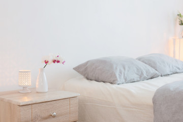 orched flowers  in vase and burning candles in white bedroom