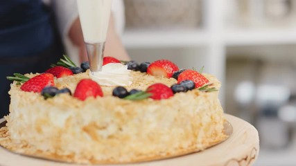 Close up adding whipped cream on cake decorated by fresh berries. Shot on RED Raven 4k Cinema Camera