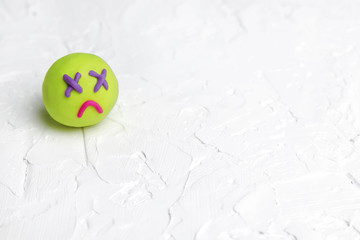 Sad face from multi-colored plasticine on a white background. Copy space - the concept of a bad mood, sadness, expression of emotions, disappointment, illness.