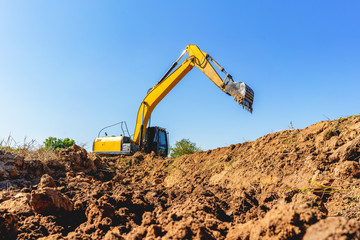 Backhoe digging up soil to prepare agricultural land.